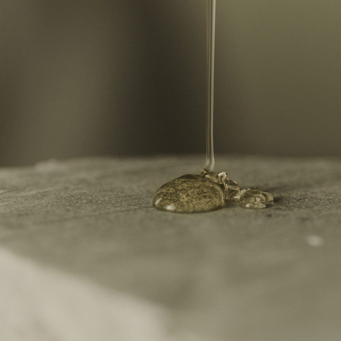 Clear amber gel being poured onto a textured stone surface.