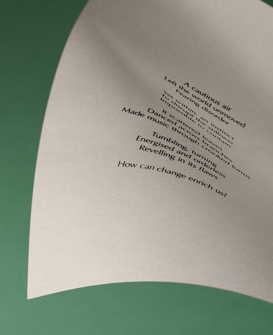 Papier creme incurve, portant le texte d’un poeme, sur fond vert sourd.