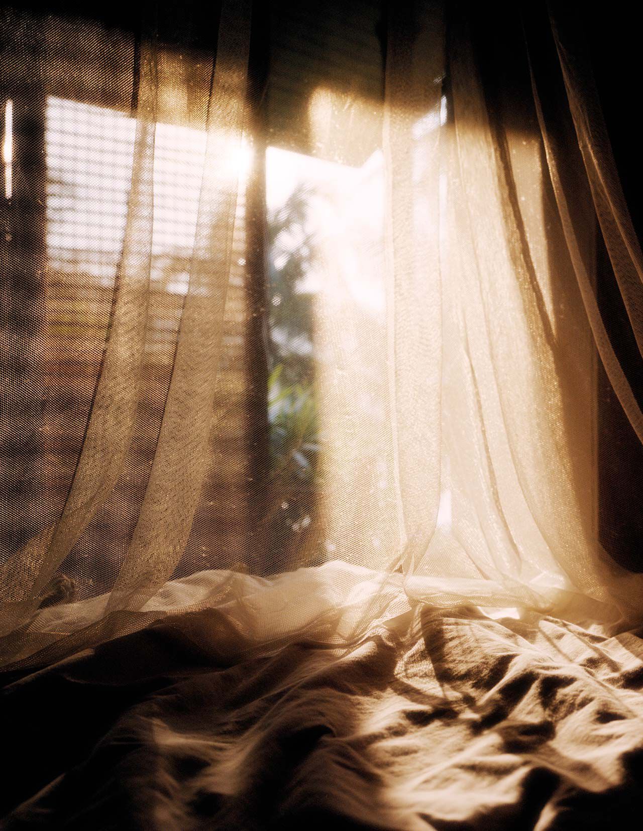 Des rideaux diaphanes drapes sur un tissu froisse pres d’une fenetre baignee de soleil, revelant des tons beige chaud, de douces ombres et des plis translucides.