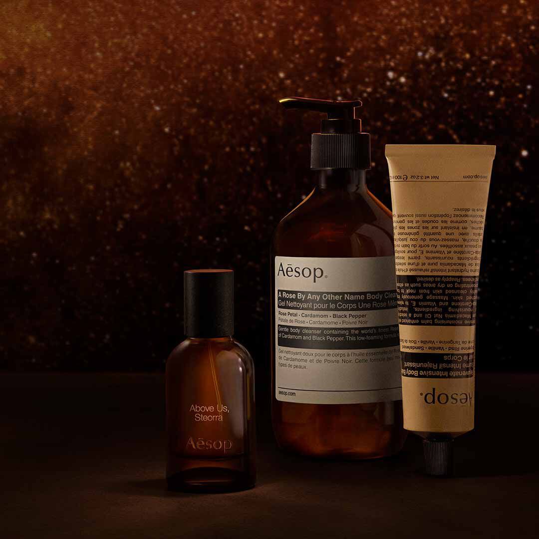 Flacon Aesop Above Us, Steorra avec flacon-pompe et tube sur un fond brun mouchete aux tons chauds.