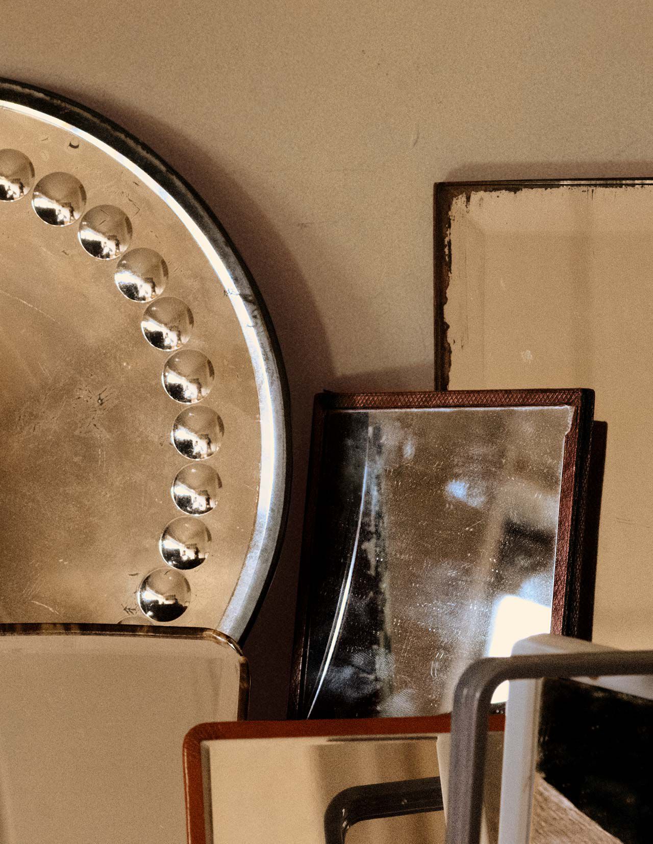 Objets metalliques et mineraux empiles, dans des tons bronze, beige et brun fonce, composes de formes geometriques superposees sur fond de mur neutre.
