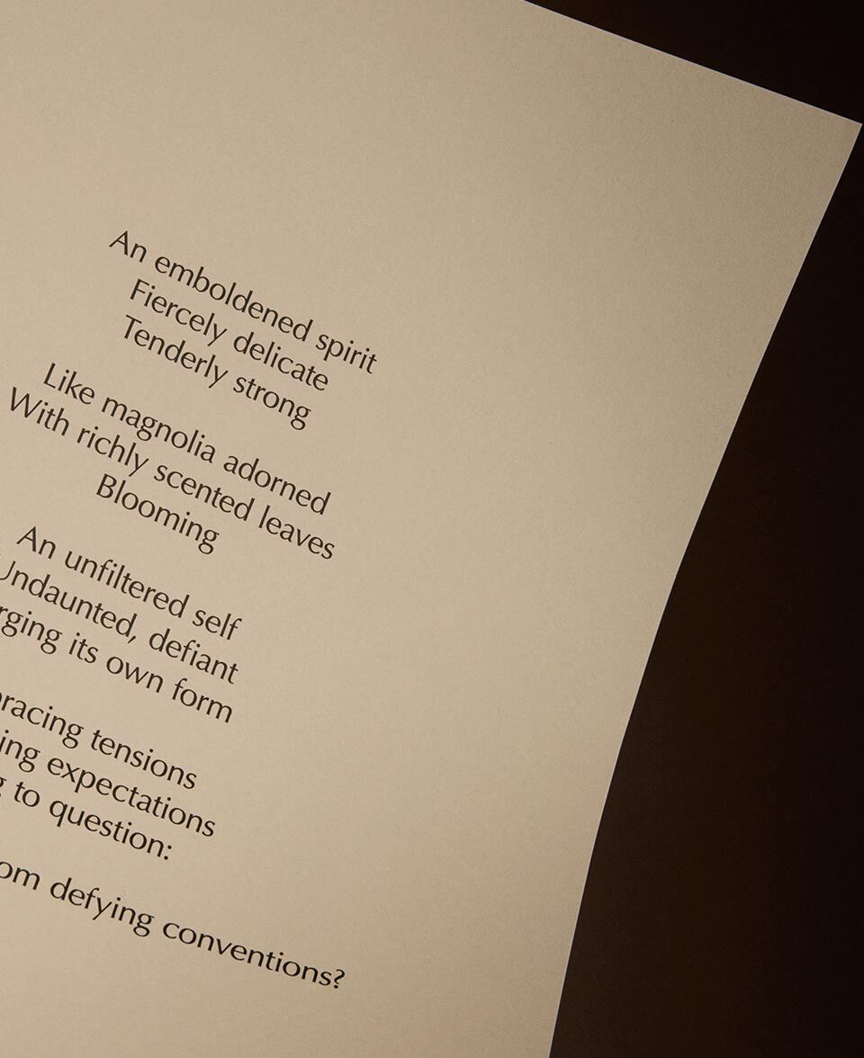 Texte de poeme sur une page creme doucement eclairee, sur fond sombre.