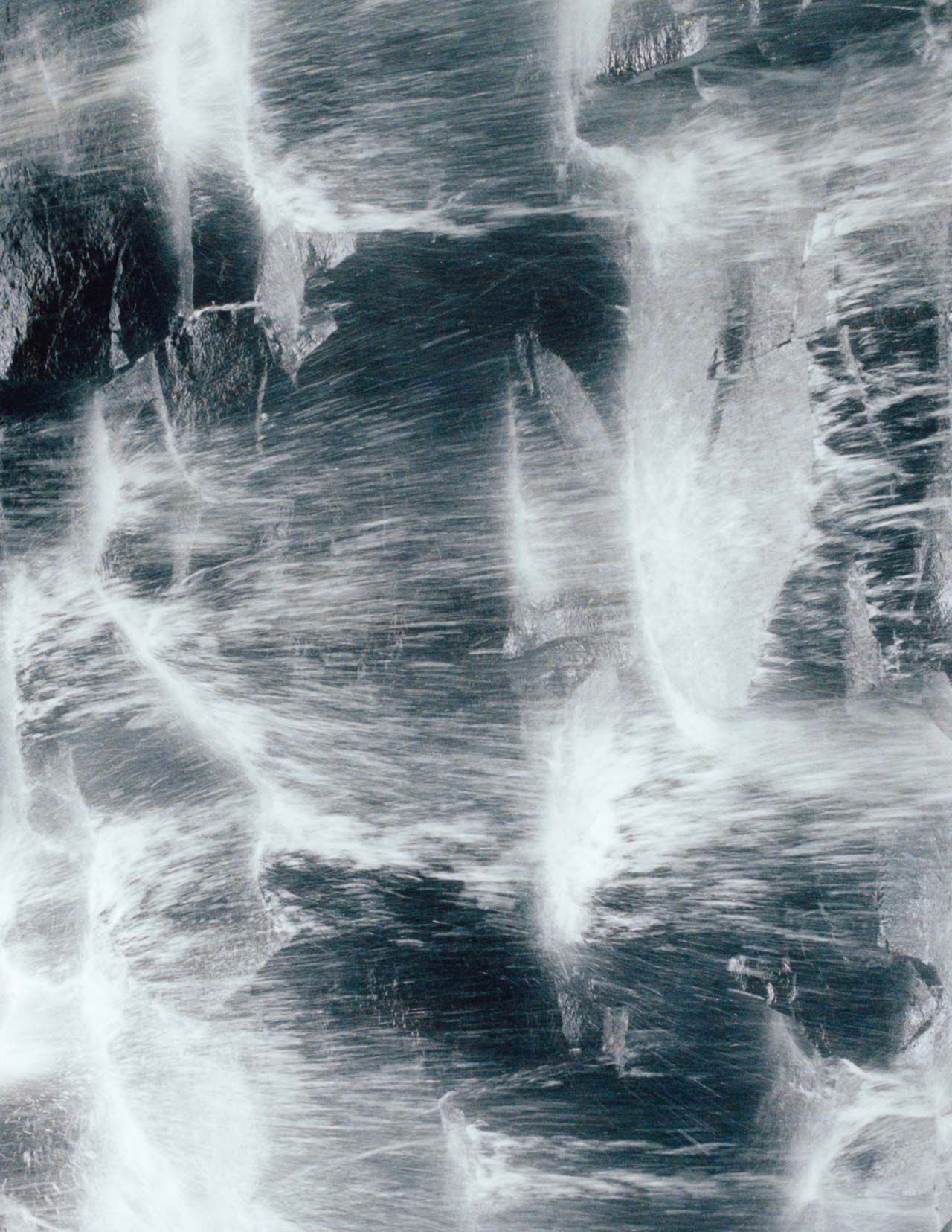 Surface rocheuse bleu gris fonce, parcourue de veines blanches et d’une texture minerale brute, formant un motif marbre tres contraste.
