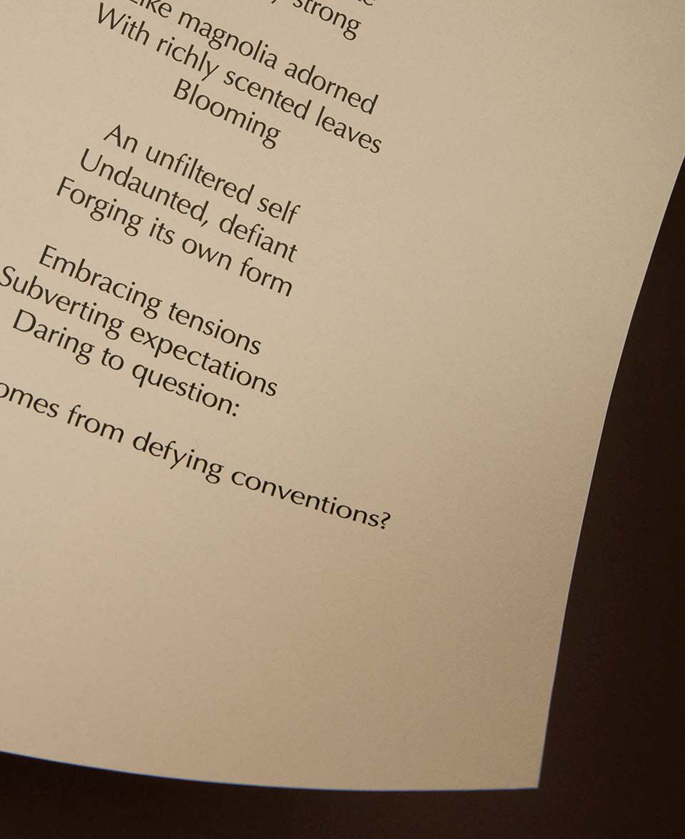 Vue partielle d’un poeme imprime sur papier creme, avec un bord de page incurve.