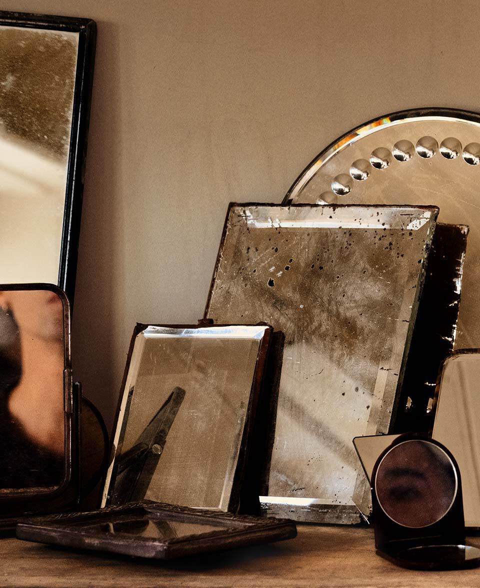 Arrangement de miroirs anciens et d’objets reflechissants sur un plateau en bois.